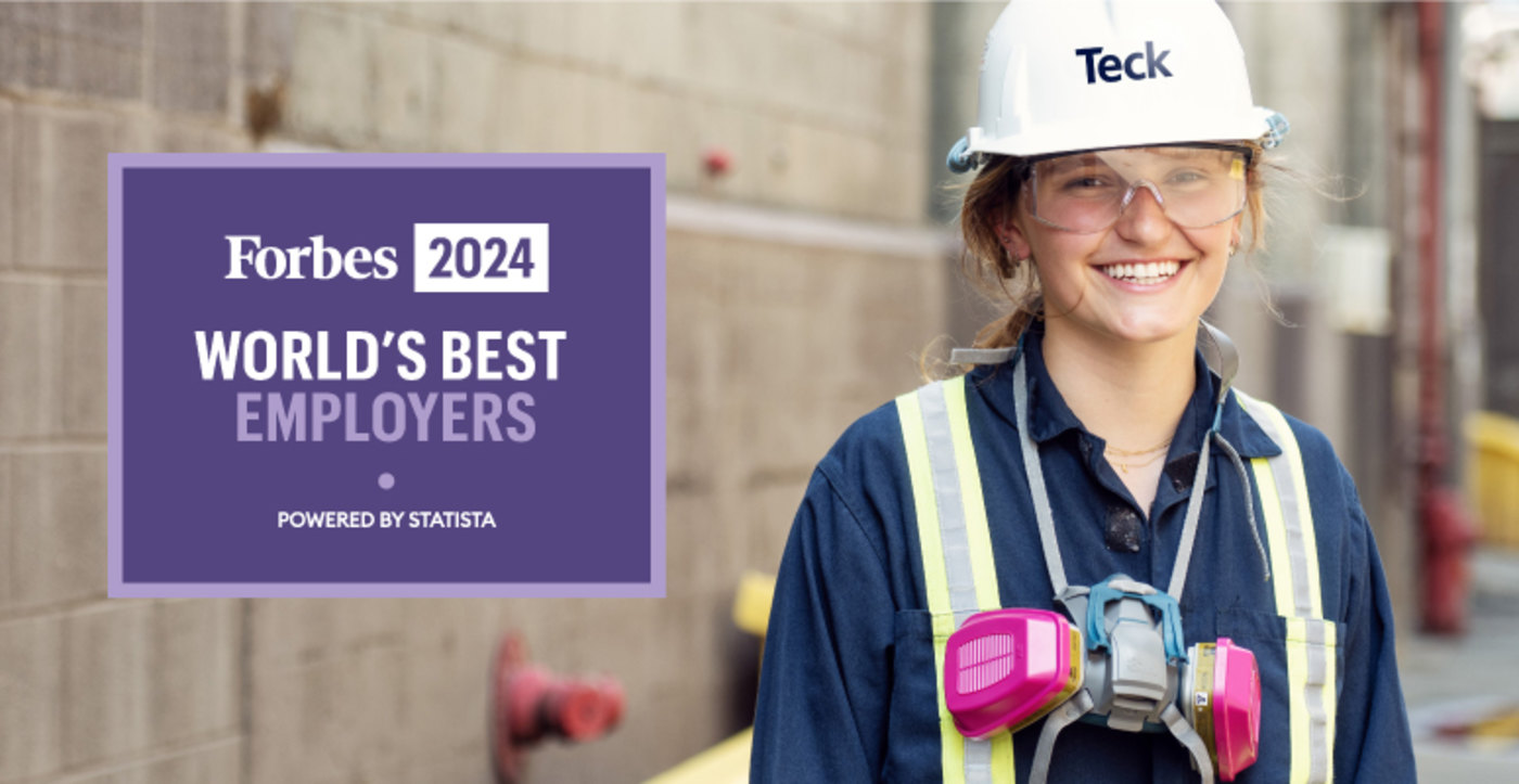 Worker in safety gear smiling beside Forbes 2024 World's Best Employers sign.